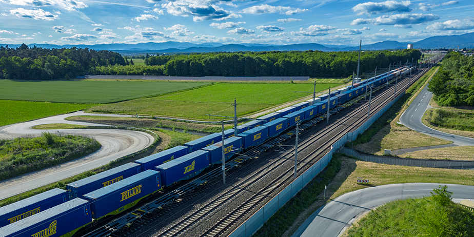 TAILWIND container train traveling through green landscapes on tracks, showcasing multimodal connections between Koper and the Graz hub in Austria.