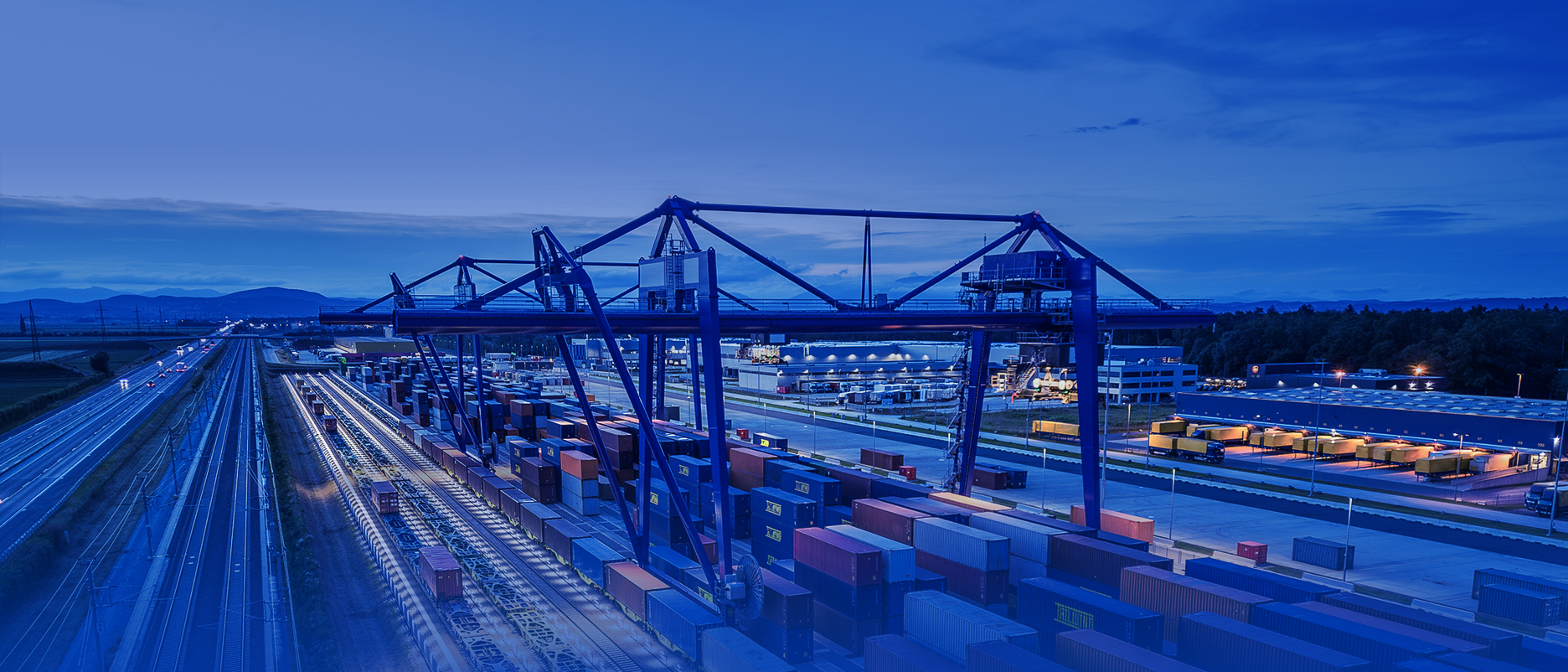 Container-Terminal Graz mit Kränen und gestapelten Containern bei Tageslicht, Schienen und moderne Infrastruktur im Vordergrund, Bewegungsunschärfe.