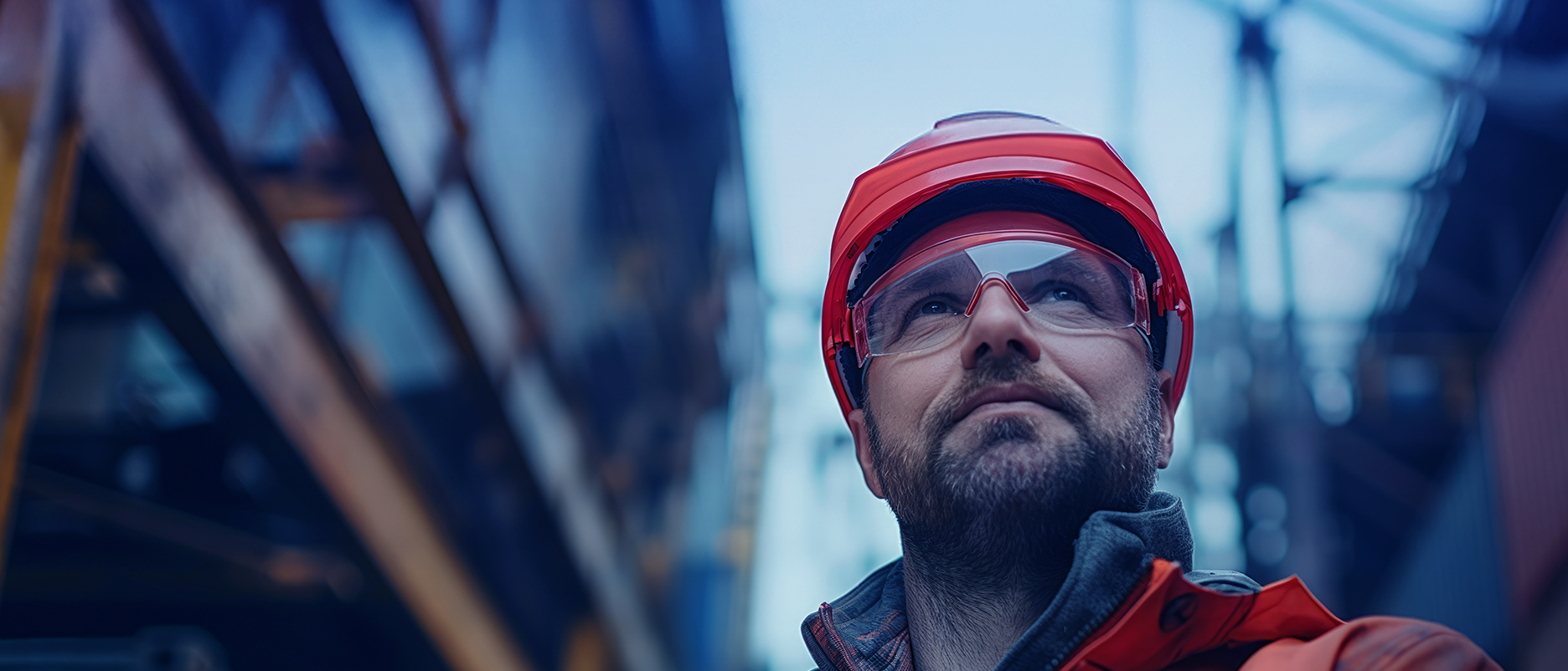 Hafenarbeiter mit rotem Schutzhelm im Industriehafen – TAILWIND Shipping Lines für verlässliche Logistik ohne Kompromisse