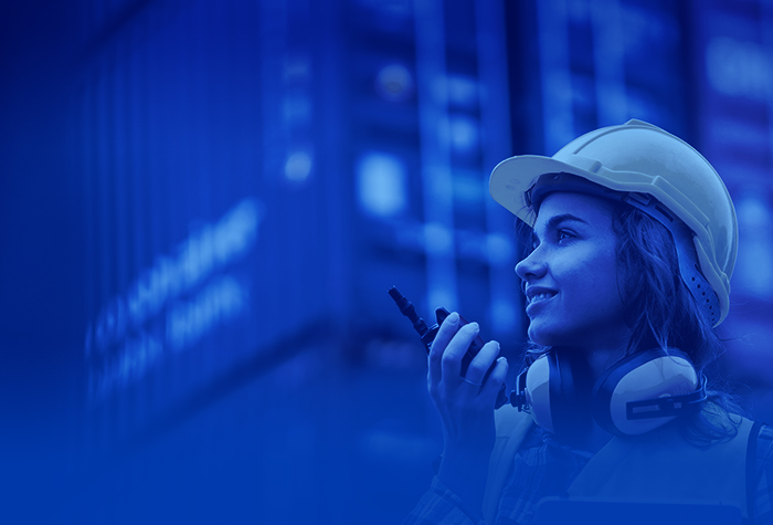Smiling female logistics employee wearing a helmet – TAILWIND Shipping Lines guarantees punctual, reliable, safe operations.
