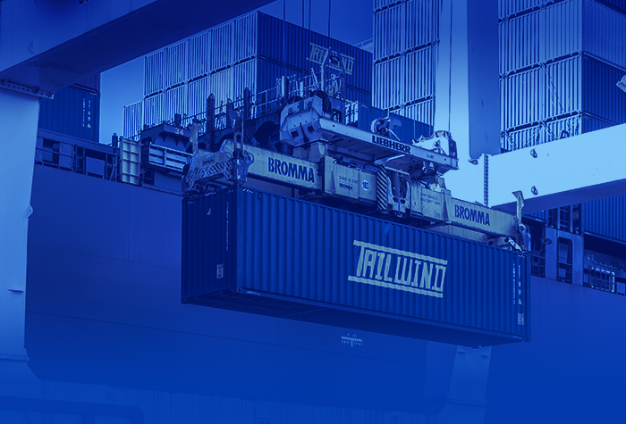 A crane holding a container in front of a vessel