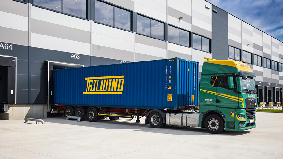 GARTNER truck with TAILWIND container standing before a warehouse