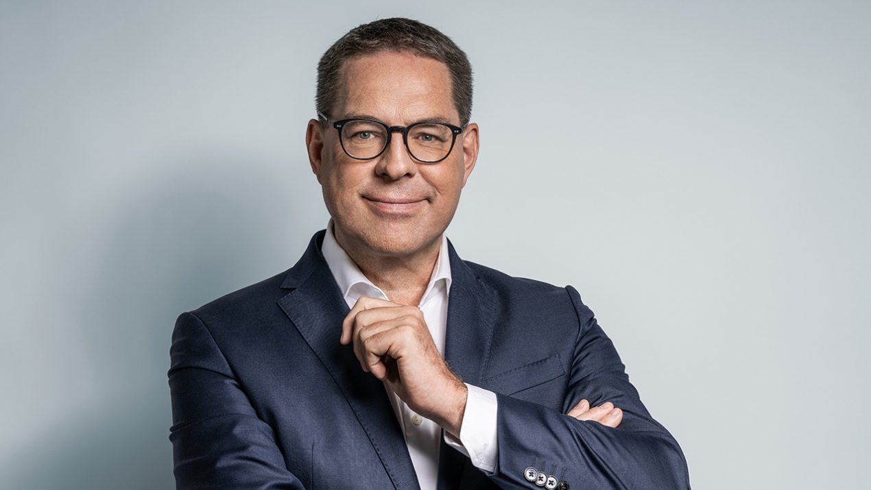 Vor einem hellgrauen Hintergrund ist Gerd Chrzanowski, Komplementär und Leiter der Schwarz Gruppe, zu sehen. Er lächelt freundlich, trägt einen dunkelgrauen Anzug mit weißem Hemd.