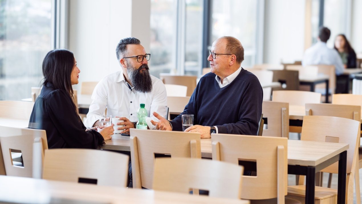 Drei Mitarbeiter sitzen an einem Tisch im Restaurant und sprechen Miteinander.