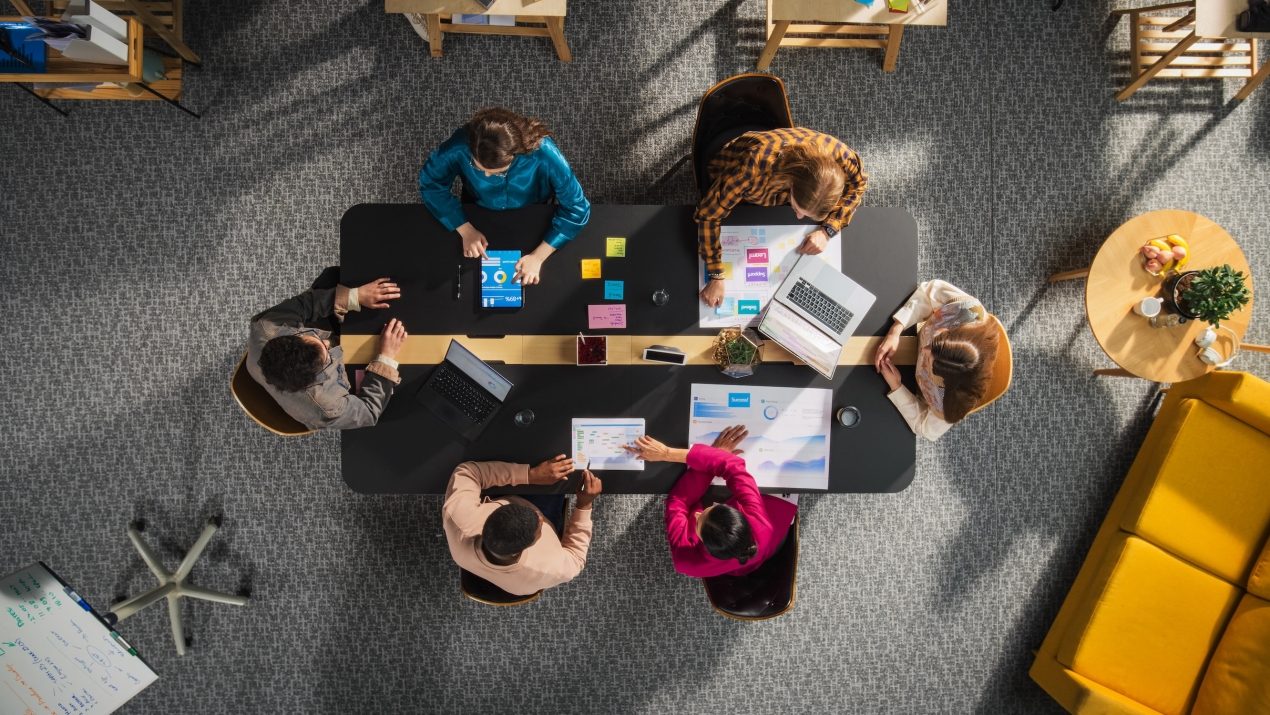 Top Down Ansicht von einem Startup Team das an einem Konferenztisch sitzt