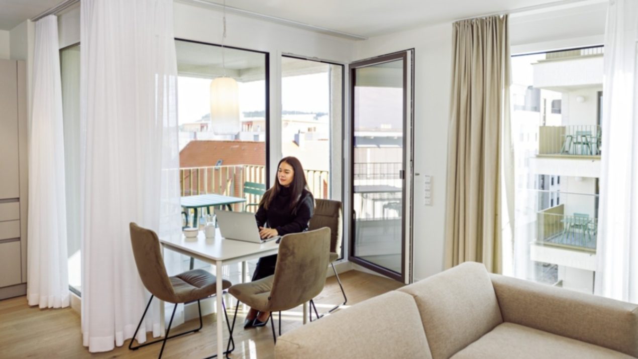 Eine Mitarbeiterin sitzt in einem Appartment und arbeitet.