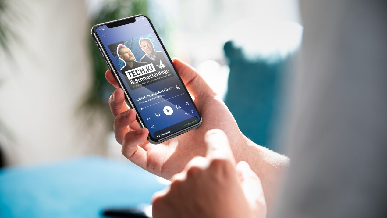 Mobiltelefon in der Hand einer Person, das den Podcast "Tech, KI und Schmetterlinge" zeigt