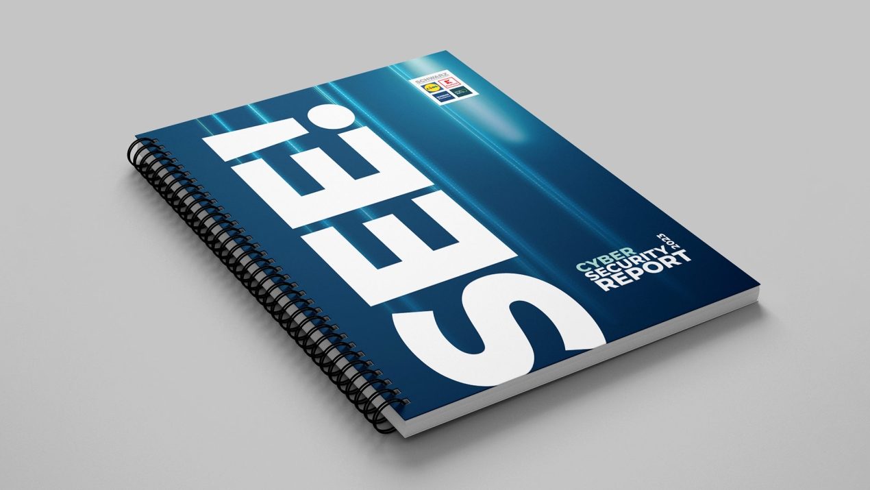 Auf einem grauen Hintergrund ist ein Ringbuch in dunkelblau und Türkis zu sehen. In weißer Schrift ist Cyber Security Report zu lesen. Links steht in großer Schrift vertikal von unten nach oben SEE!