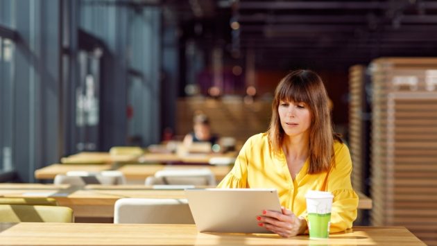 Eine Mitarbeitern der SIT sitzt an einem Laptop im Restaurant und arbeitet remote.