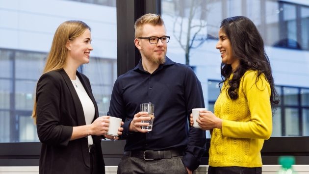 Drei Mitarbeiter der SIT stehen zusammen in einem Konferenzraum und sprechen miteinander.