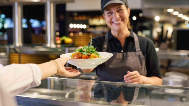 Frau übergibt Mittagessen im Restaurant an Person aus