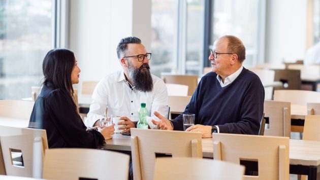 Drei Mitarbeiter sitzen an einem Tisch im Restaurant und sprechen Miteinander.