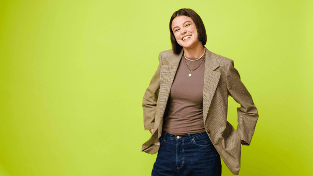 Junge Frau mit Blazer steht und lacht
