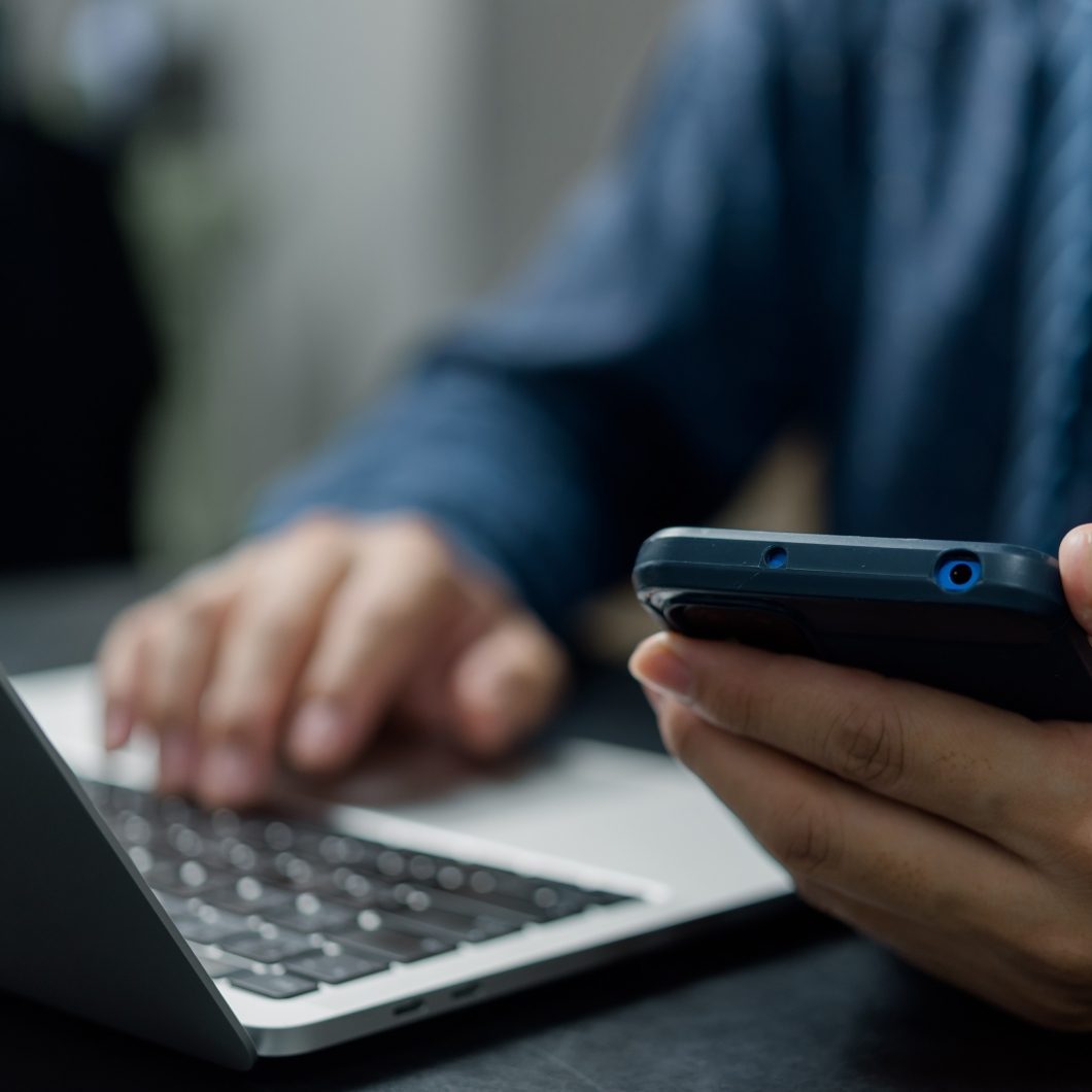 Man with cell phone in hand and laptop open.