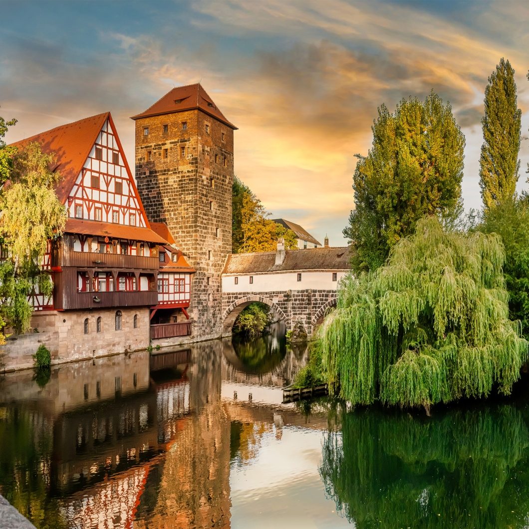 Historic Weinstadel and Henkersteg covered bridge over the Pegnitz river in Nuremberg at sunset.