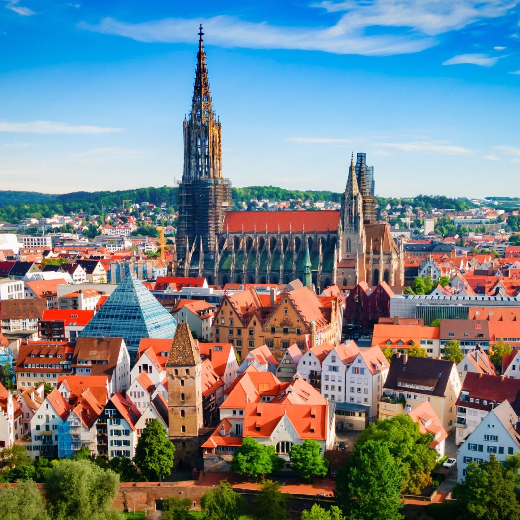 Scenic panoramic view of the city of Ulm, Germany, featuring the prominent Ulm Minster and traditional architecture under a clear blue sky – a perfect visual for regional cloud events in the Southern German tech hub.
