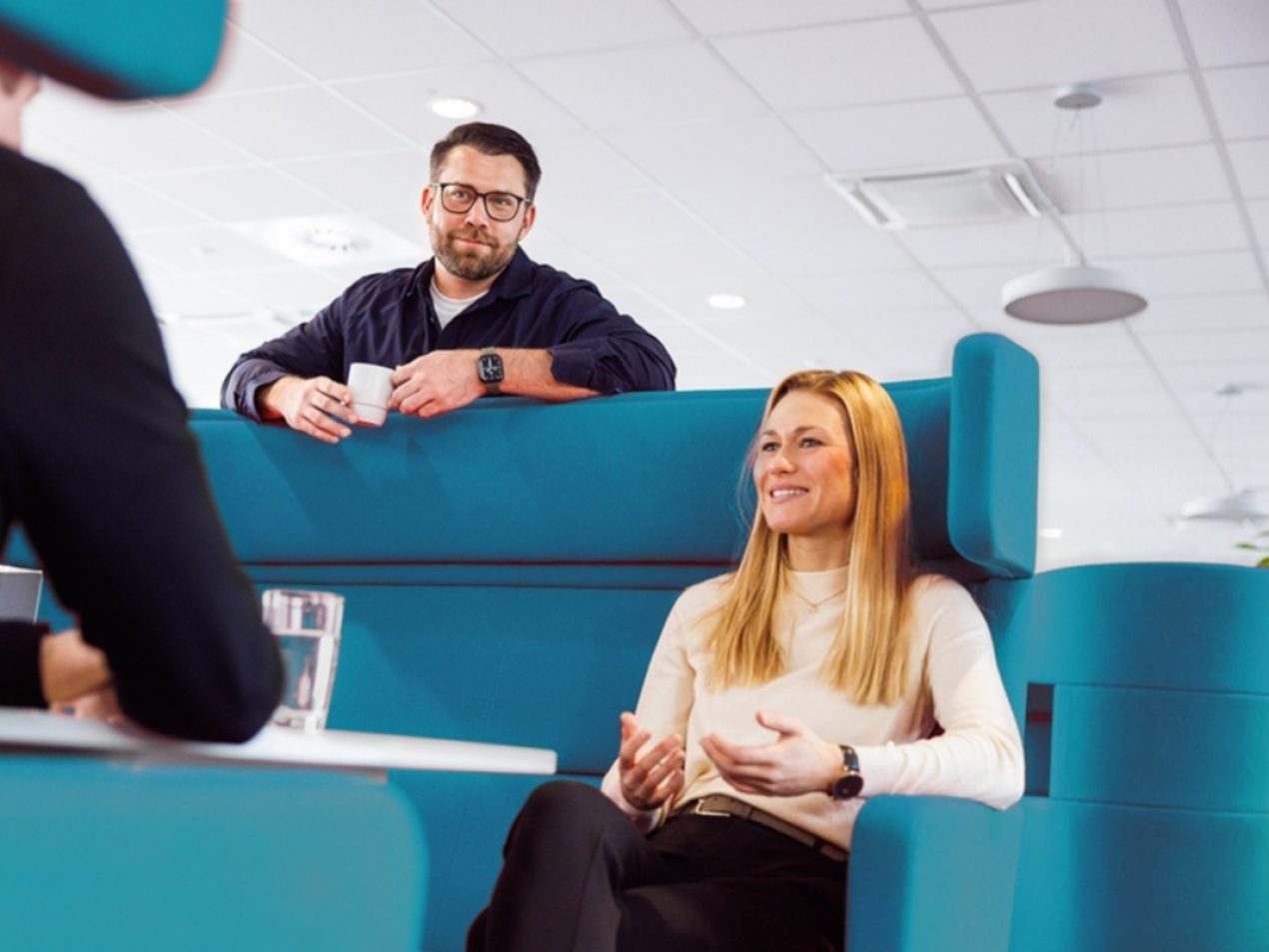 Drei Mitarbeiter der SIT sitzen in einer Besprechungslounge zusammen und sprechen miteinander.