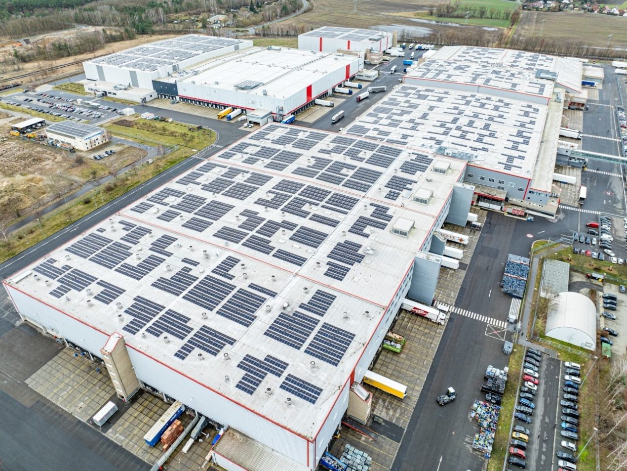 Luftaufnahme des Kaufland Logistikzentrums mit großflächiger Solaranlage auf den Dächern und mehreren Laderampen.