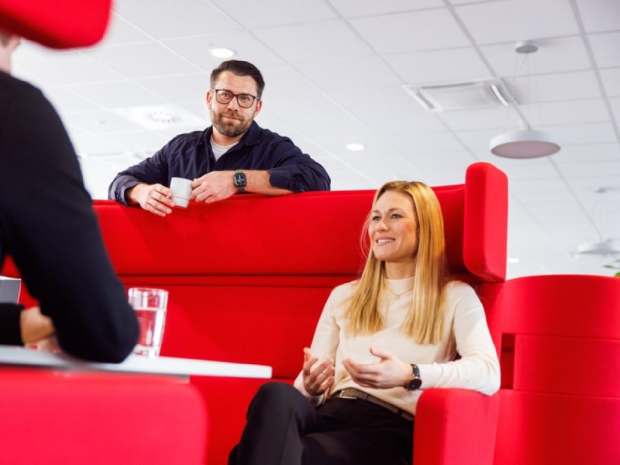Drei Mitarbeiter unterhalten sich in einer Besprechungslounge.