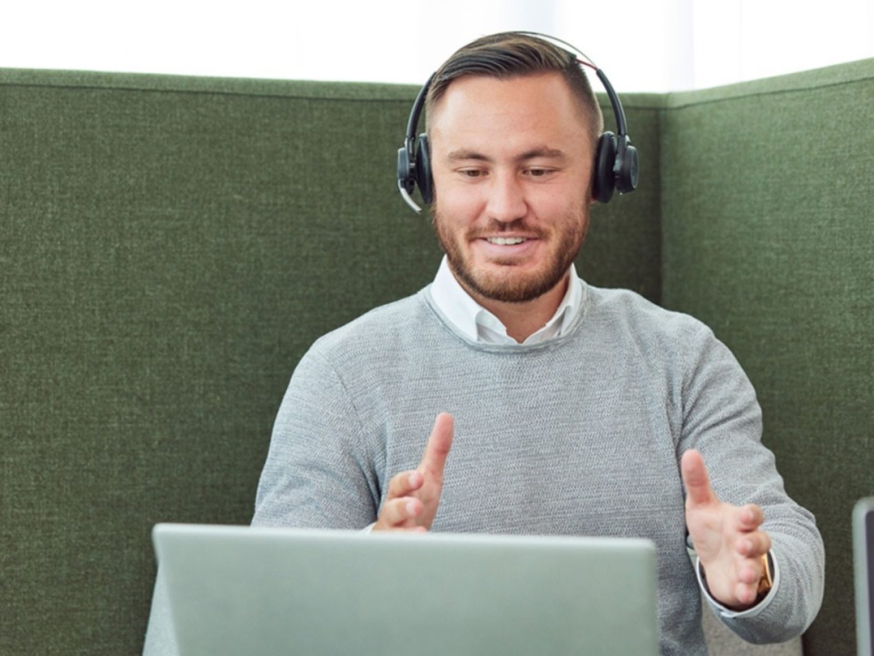 Ein Mitarbeiter sitzt in einer Besprechungslounge und nimmt an einem Meeting via Teams teil.