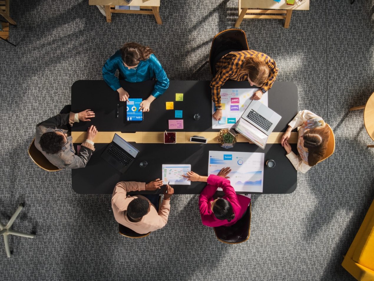 Top Down Ansicht von einem Startup Team das an einem Konferenztisch sitzt
