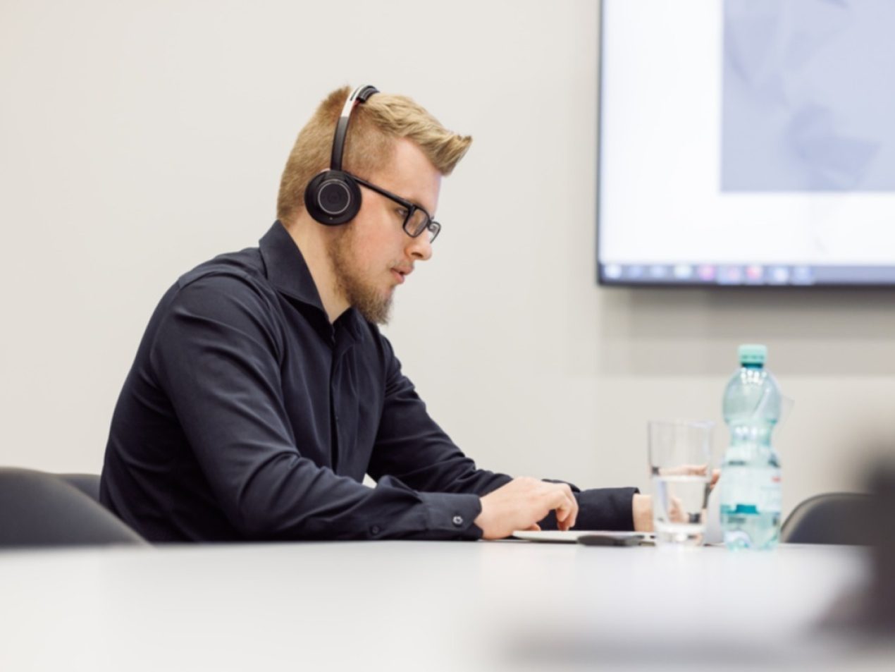 Ein Mitarbeiter sitzt in einem Konferenzraum und schaut auf seinen Laptop.