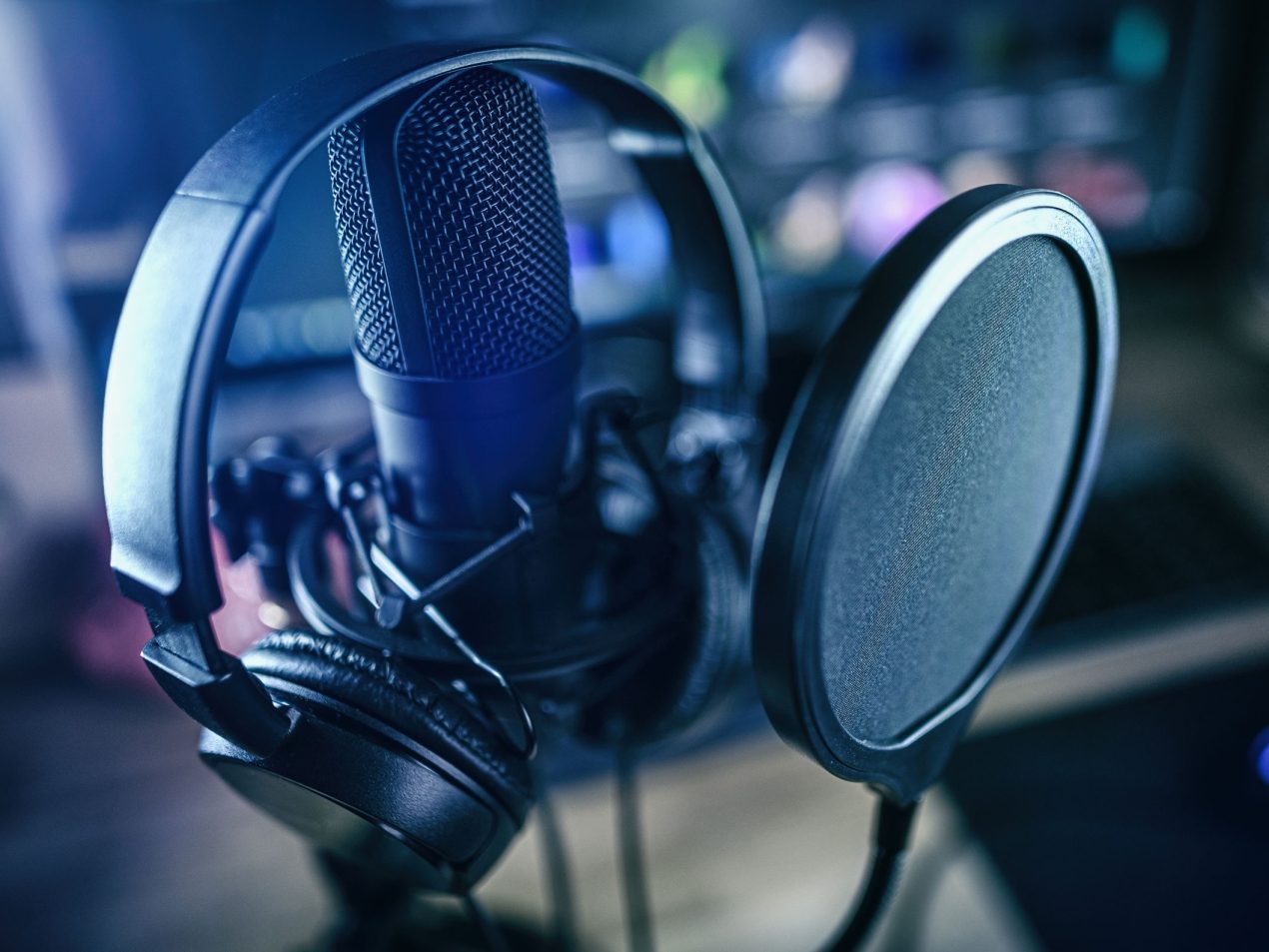 Nahaufnahme eines professionellen Studio-Mikrofons mit Poppschutz und Kopfhörern. Symbolisiert Audio-Produktion, Podcast-Aufnahme, Streaming oder professionelle Sprachaufnahme.