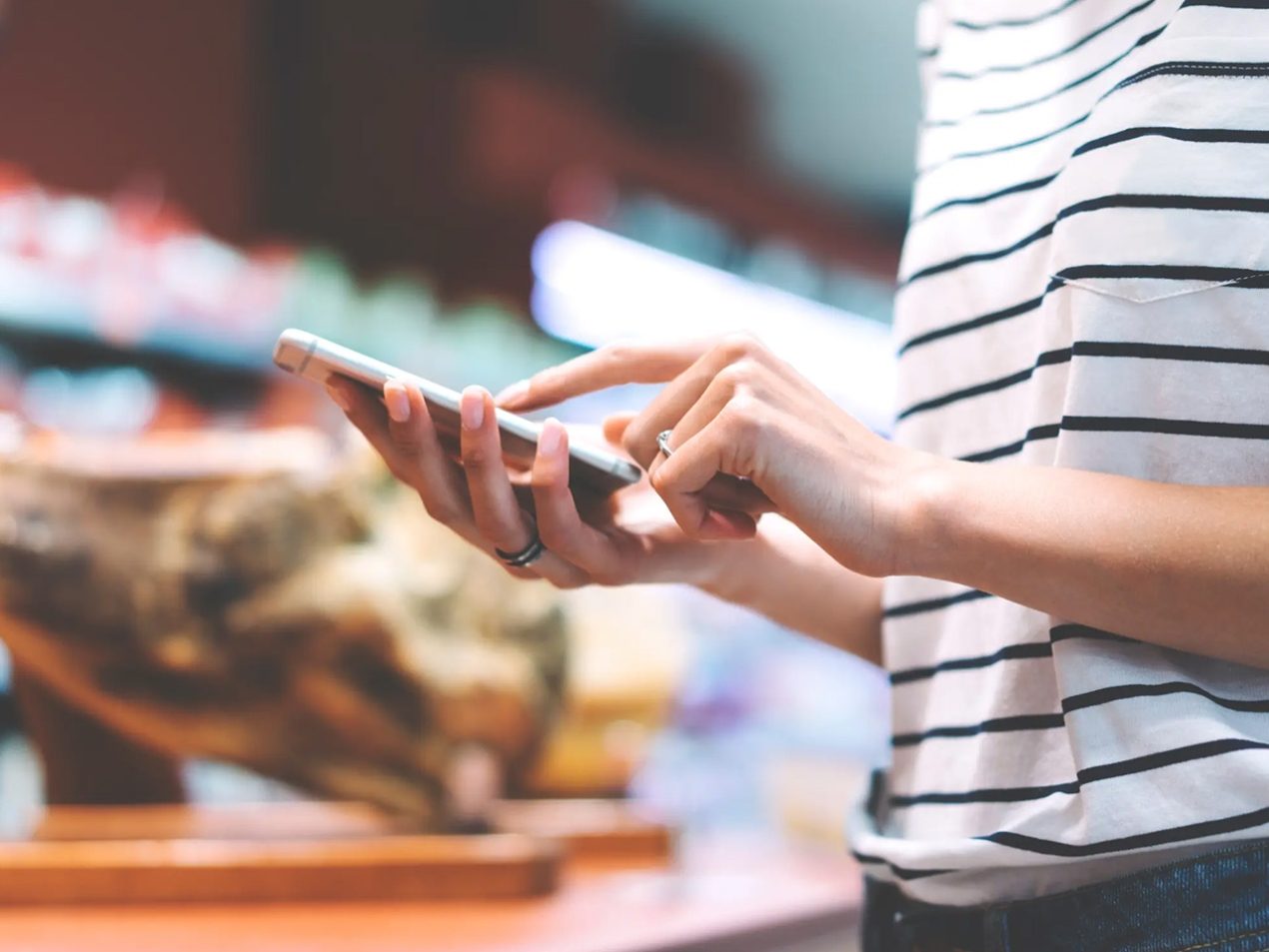 Frau im Supermarkt tippt etwas in ihr Handy