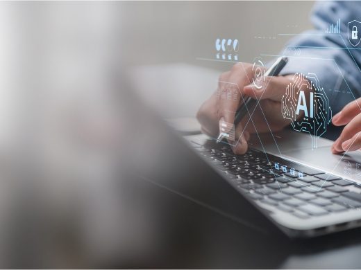 Close-up of hands working on a laptop while holding a stylus pen, overlaid with blue digital graphics showing an AI brain icon, security shield, folders, and document management interfaces. This image is AI-generated.