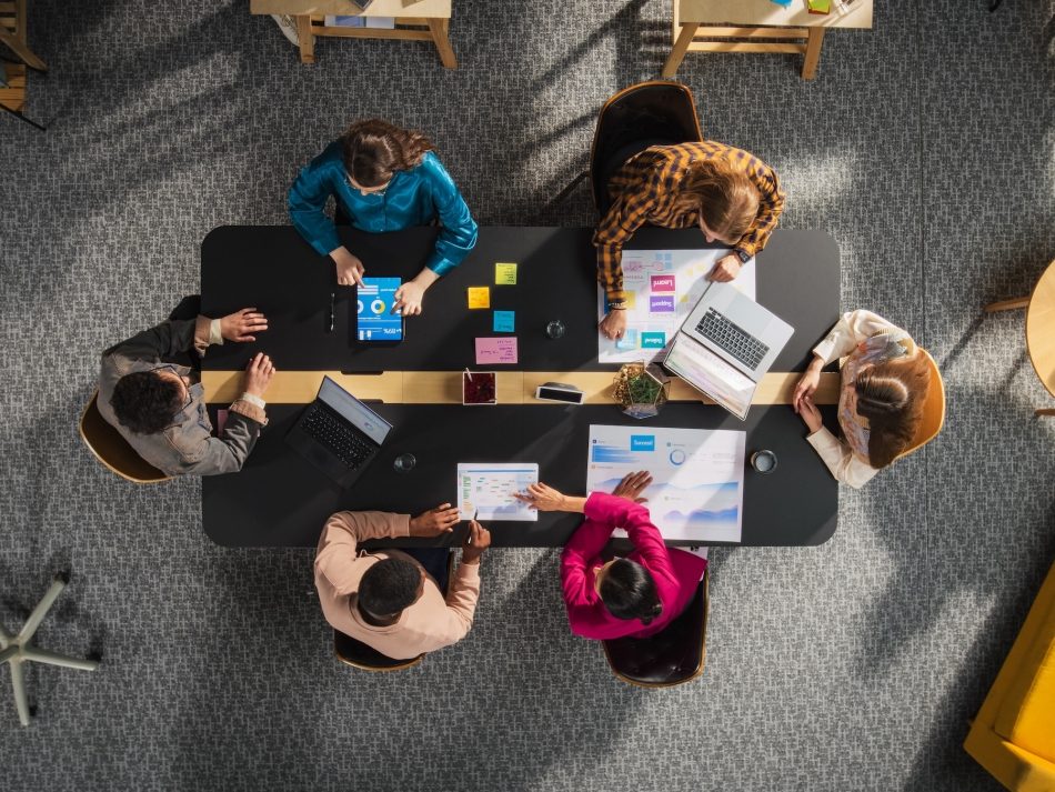 Top Down Ansicht von einem Startup Team das an einem Konferenztisch sitzt