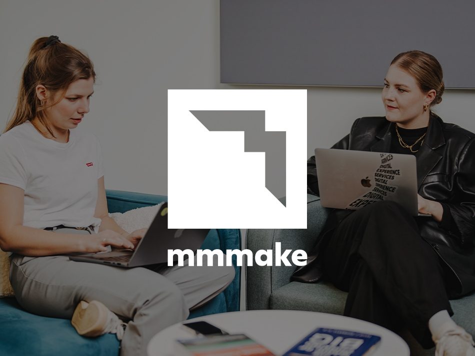 Das mmmake-Logo zentriert im Vordergrund; im Hintergrund sitzen zwei Frauen mit Laptops im Büro.
