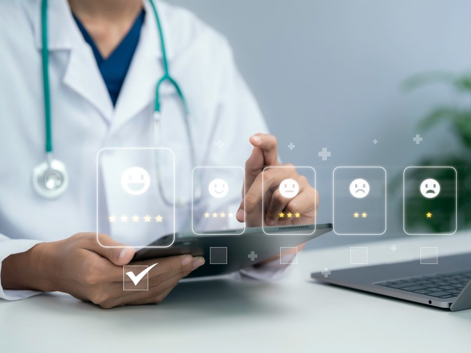 Doctor in a white coat using a tablet to evaluate patient satisfaction ratings with digital smiley icons.