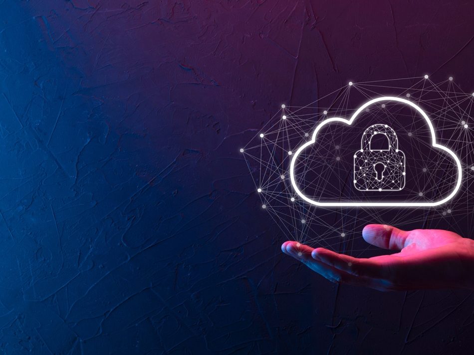 Eine Hand hält eine schwebende, leuchtend weiße Cloud-Grafik mit einem Vorhängeschloss-Symbol im Inneren. Die Cloud ist von einem digitalen Netzwerk aus Punkten und Linien umgeben. Der Hintergrund ist eine dunkle Wand, beleuchtet von blauem und pinkem Neonlicht. Das Bild symbolisiert Cloud-Sicherheit, Datenschutz und den Schutz digitaler Infrastrukturen.