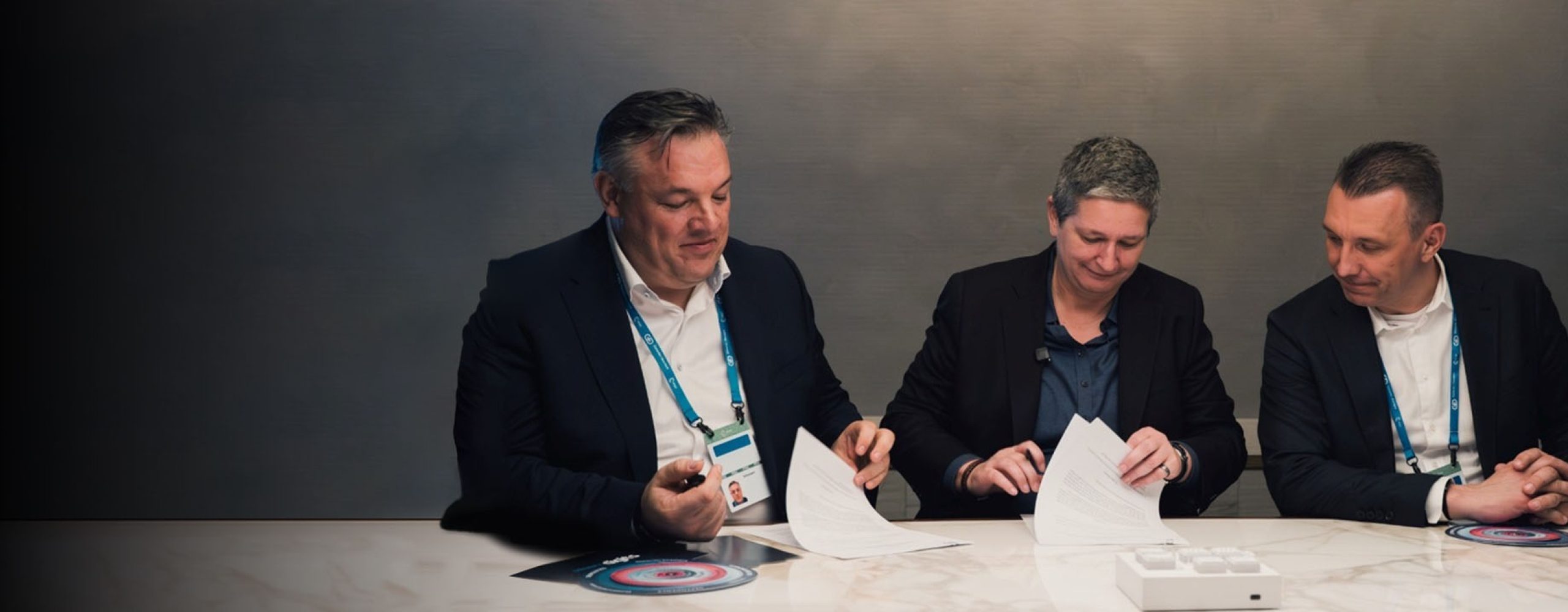 Digital Souveränität gemeinsam gestalten: In der Mitte BSI-Präsidentin Claudia Plattner, links und rechts die Schwarz Digits Co-CEOs Rolf Schumann und Christian Müller beim Sichten und Unterzeichnen von Dokumenten.