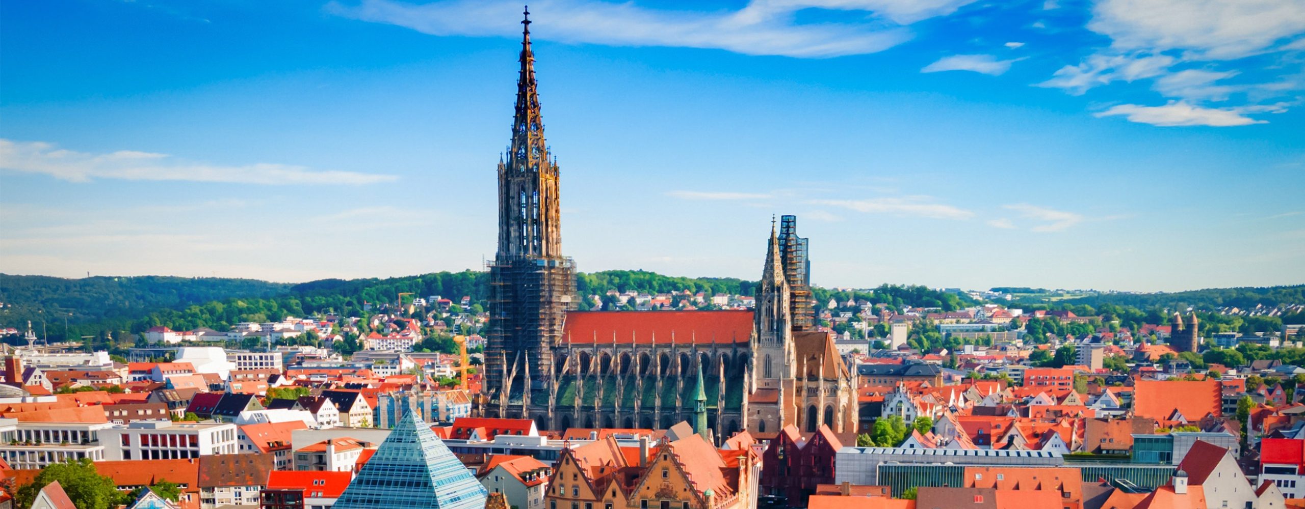 Scenic panoramic view of the city of Ulm, Germany, featuring the prominent Ulm Minster and traditional architecture under a clear blue sky – a perfect visual for regional cloud events in the Southern German tech hub.