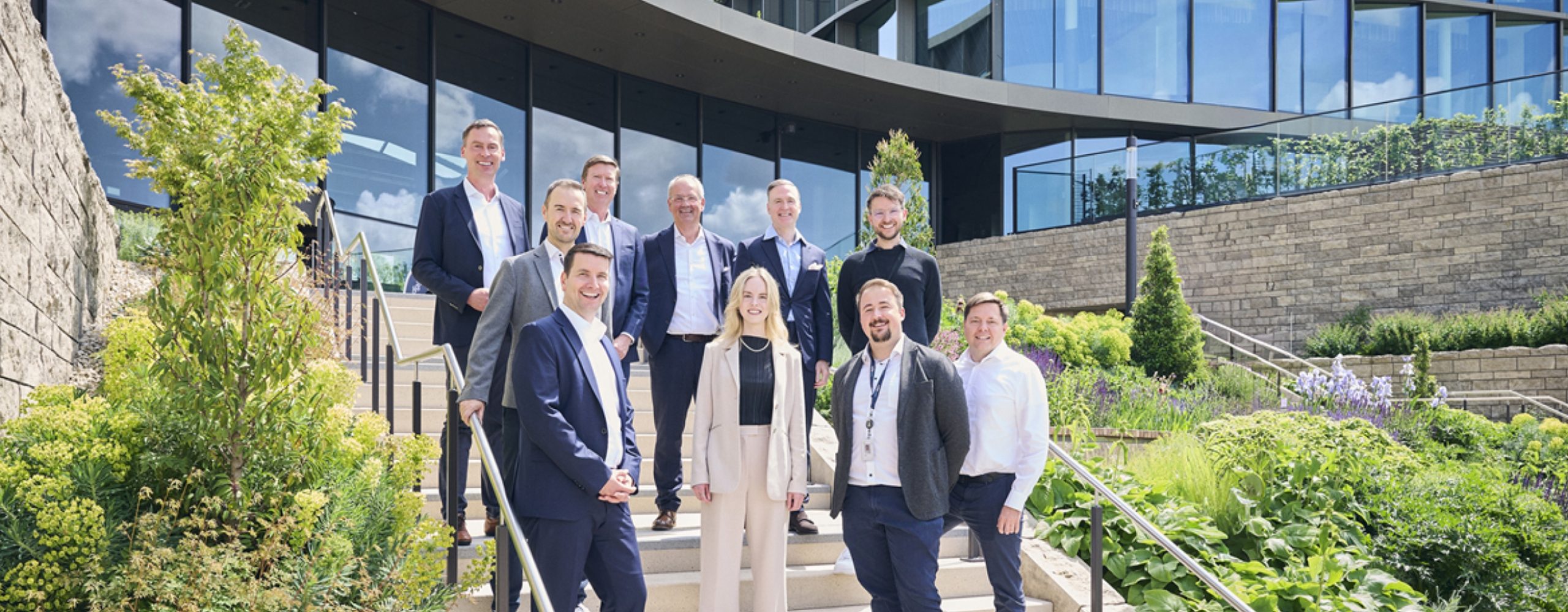 Schwarz Digits and Zscaler team standing on outdoor stairs in front of a modern office building