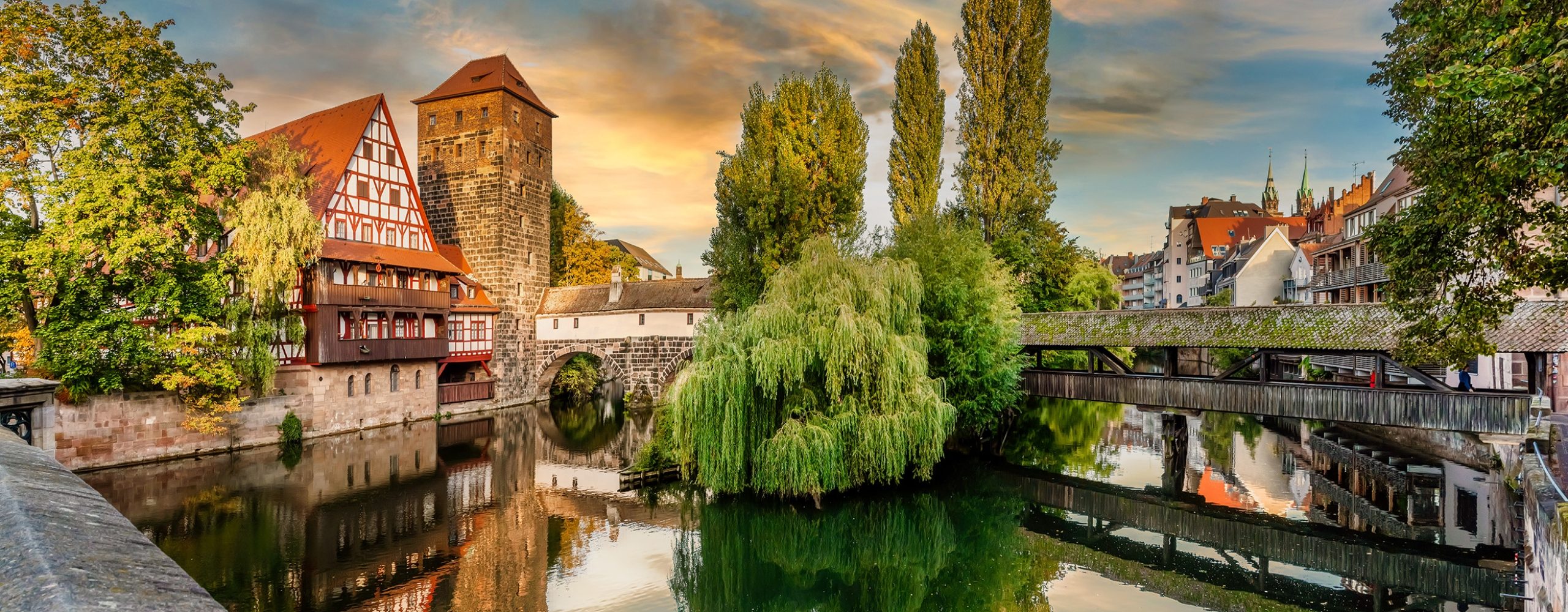 Historic Weinstadel and Henkersteg covered bridge over the Pegnitz river in Nuremberg at sunset.