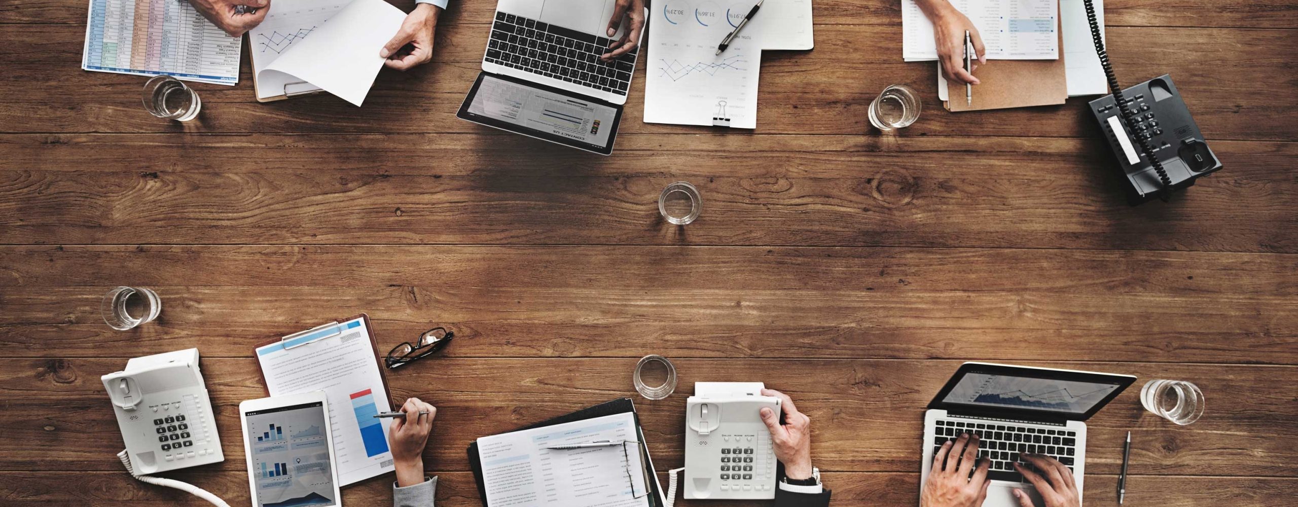 Team in business analysis (overhead view). On the table are financial reports, graphics and technical devices.